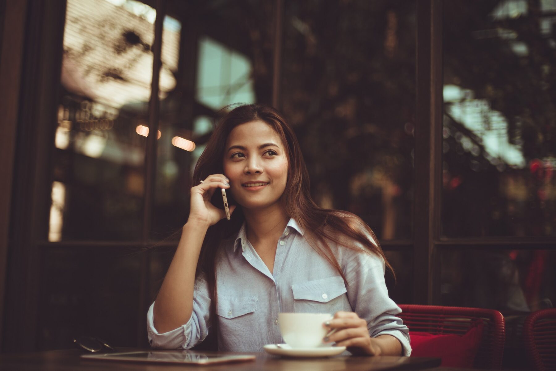 Woman sitting outside a cafe talking on phone