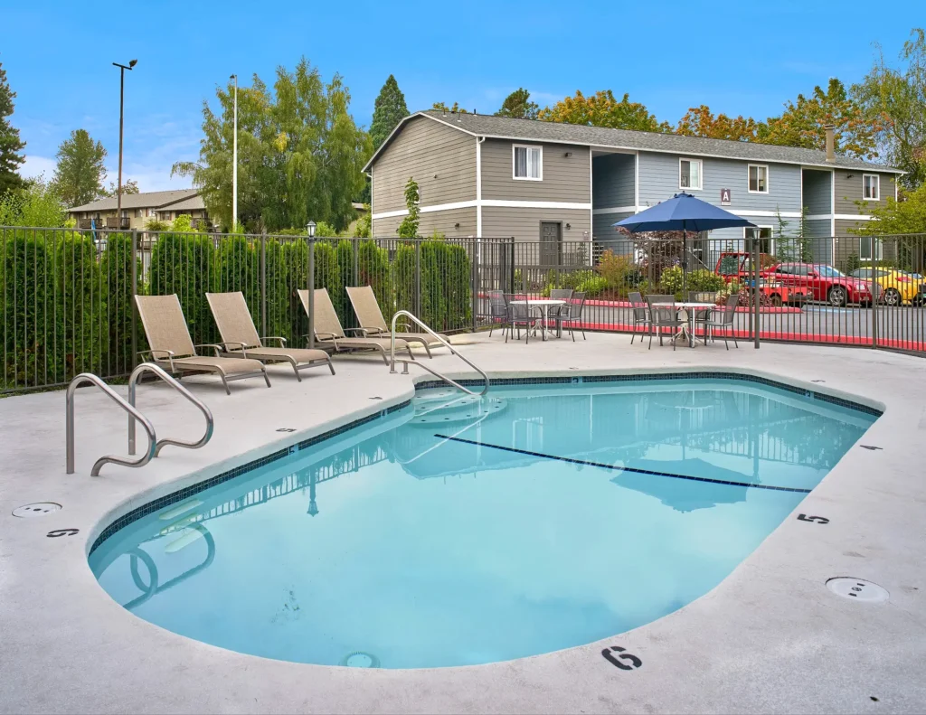 Outdoor pool with lounge poolside seating and tables at Irwin Park pet-friendly apartments in Kent, WA
